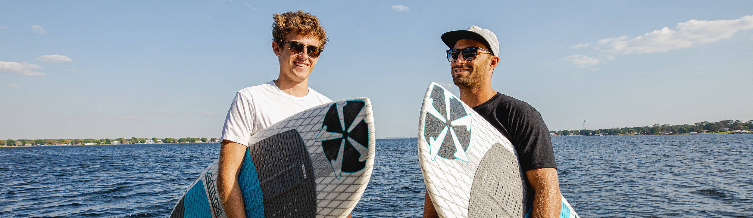 John Akerman and a teammate holding Phase Five wakesurf boards on a lake