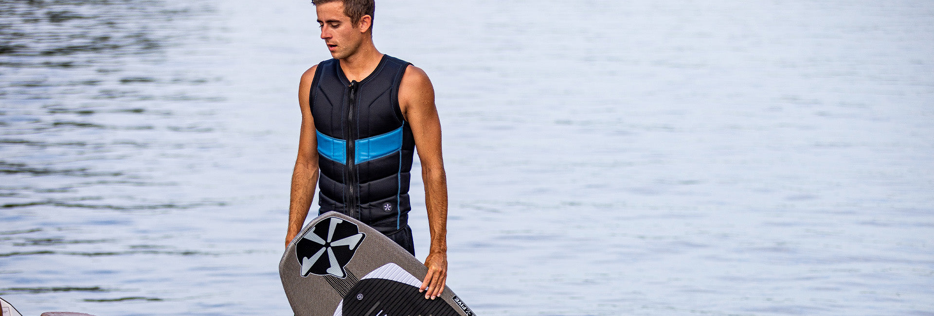 Parker Payne holding a Phase Five board by the water