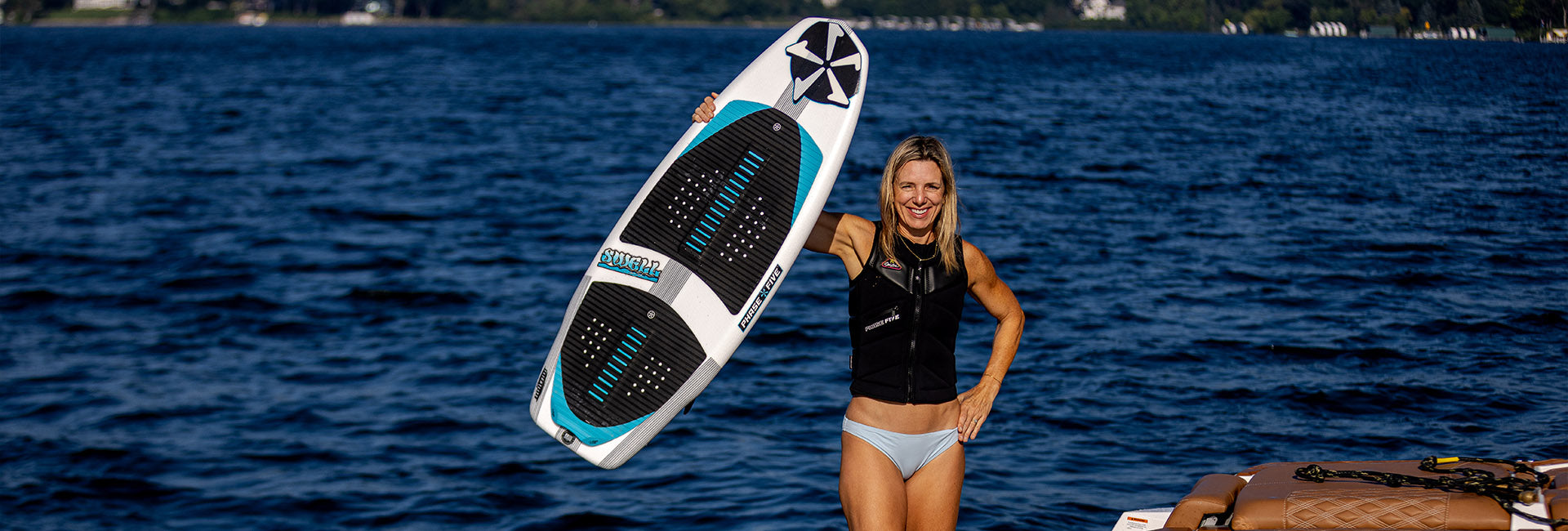 Stacia Bank holding a Phase Five Swell board on the water